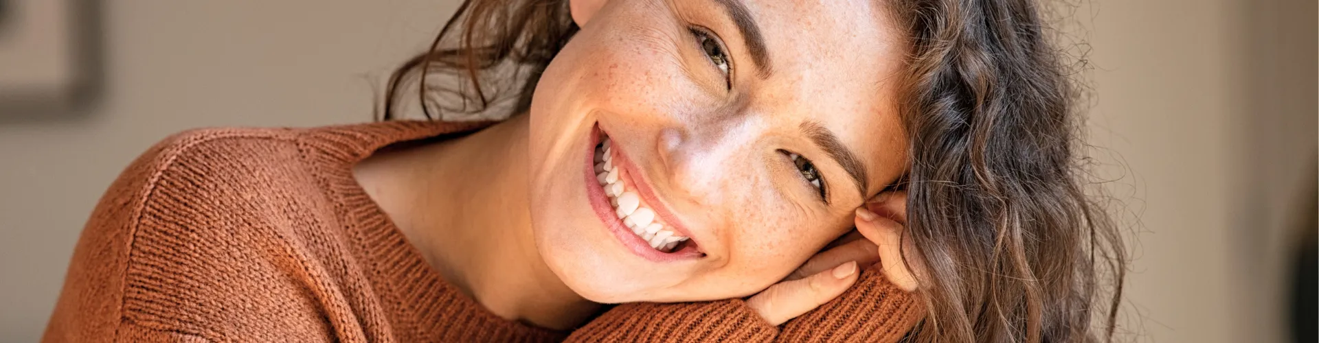 Smiling woman tilting her head into her hand.