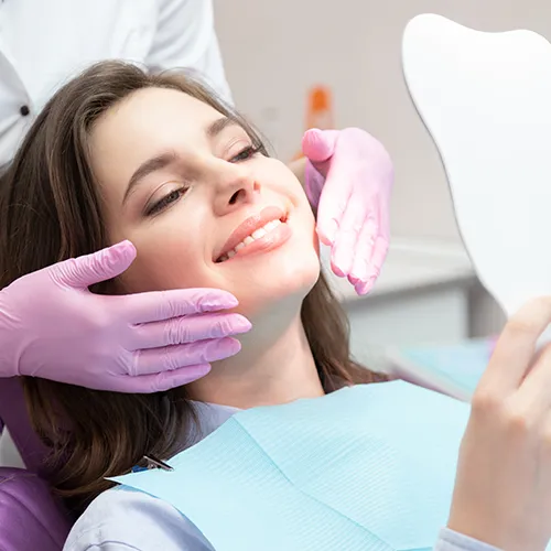 Gloved hands framing smile of woman looking in hand mirror.