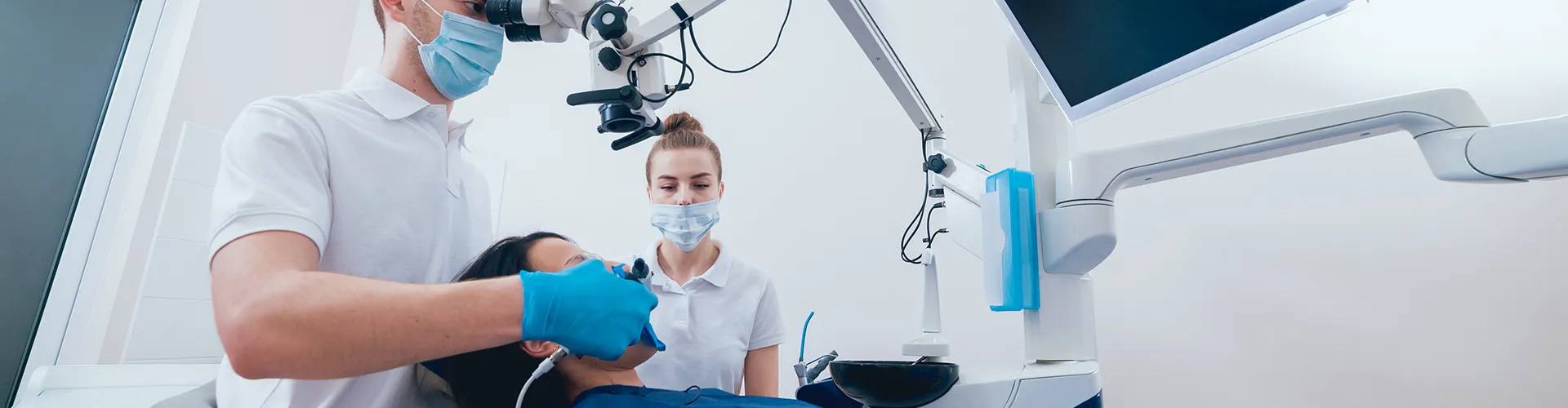 Patient in dental chair receiving treatment from dentist.