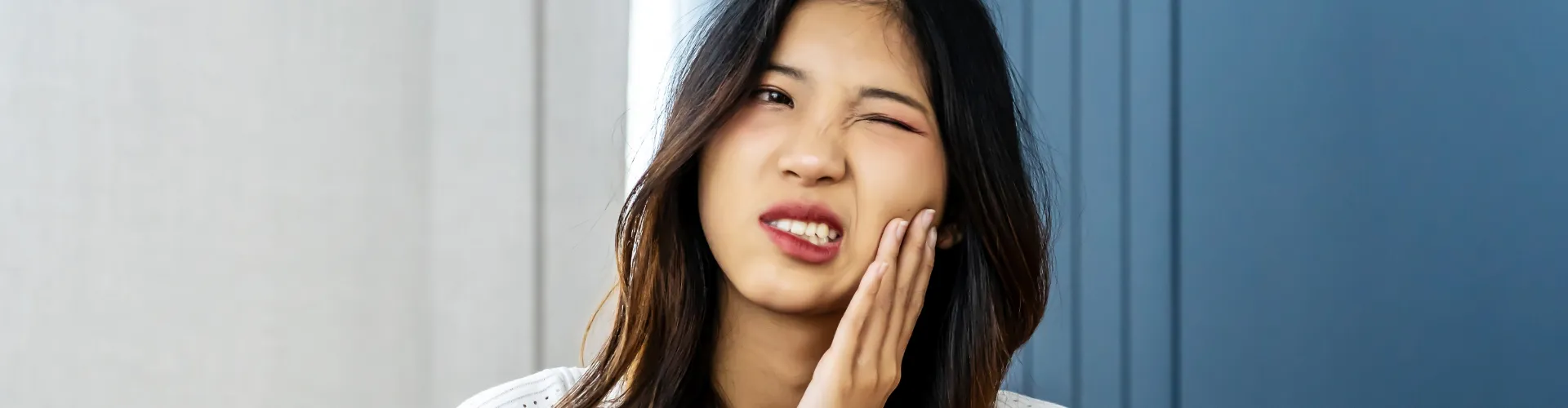 Woman holding her cheek in pain.