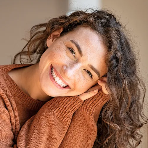 Smiling woman tilting her head into her hand.
