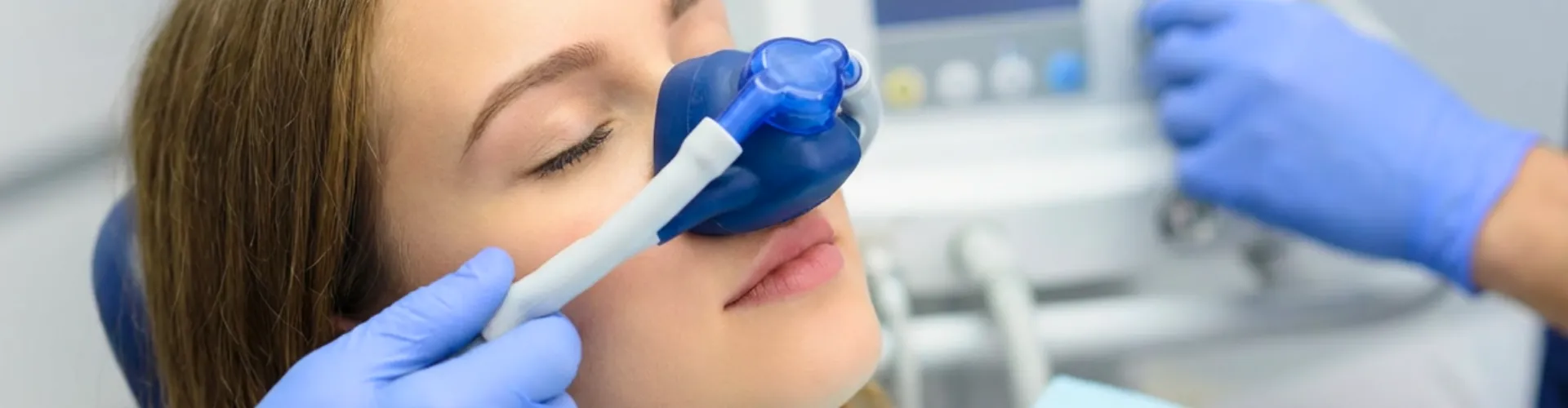 Gloved hands placing breathing mask over woman's nose.