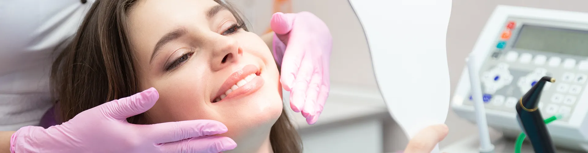 Gloved hands framing smile of woman looking in hand mirror.