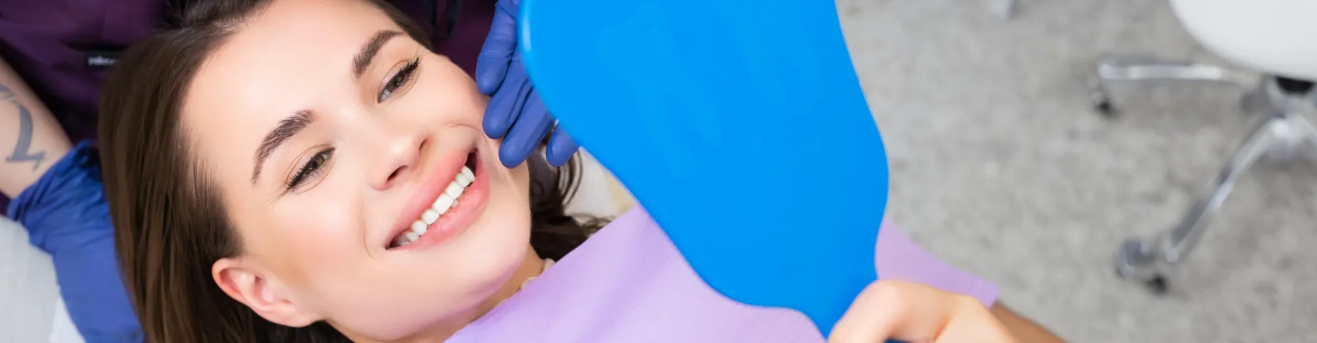 Smiling patient checking results after professional teeth whitening treatment in an Encino dental office.